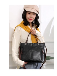 Close-up of black PU leather tote bag with brown handles and functional front zippers
