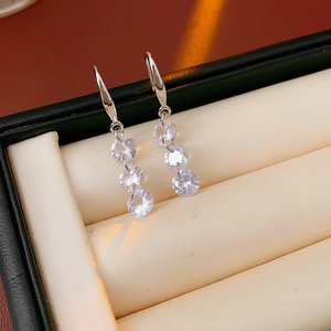 Detail view of silver drop earrings with three round zircons in a jewelry gift box