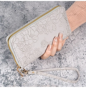 Detailed view of light grey women's long wallet with 3D floral relief and gold zipper