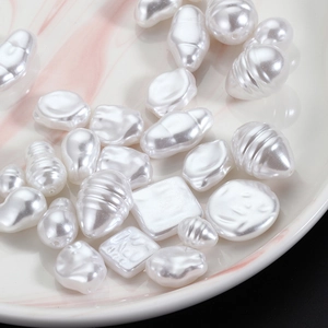 Mix of baroque irregular white faux pearls in drop and square shapes on a marble tray