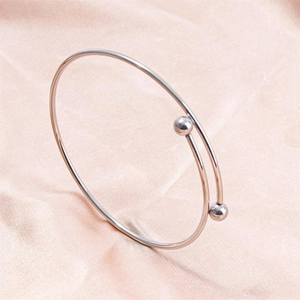 Detail shot of a silver adjustable stainless steel cuff bracelet on soft silk fabric