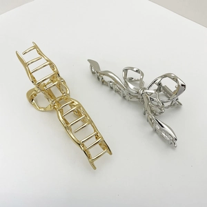 Gold and silver metal claw clips with bow and geometric designs on white background