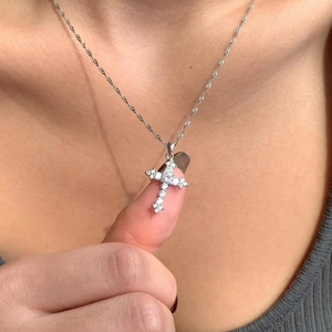 Macro shot of silver cross pendant with sparkling zircons worn by a model