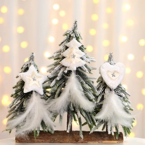 Close-up of three snowy mini Christmas trees on a wooden base with feather details
