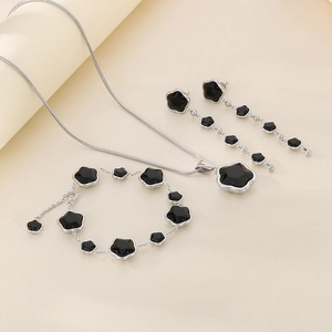 Detailed view of silver necklace and bracelet with black clover charms and fringe earrings