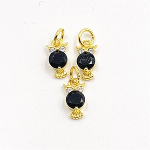 Macro detail of golden owl charms with black stones and tiny sparkling zircon settings