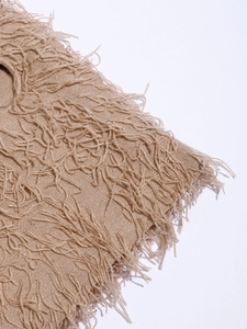 Detailed macro view of the sand beige knitted fabric texture and decorative fringe trim