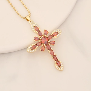 Detail of 18K gold cross pendant featuring orange marquise stones and zircon micro-inlay