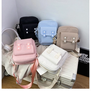 Close-up of small minimalist canvas crossbody bags in five colors on a suitcase