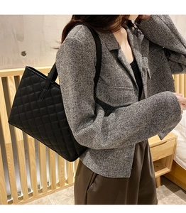 Lifestyle shot of a woman carrying a black quilted leather tote bag with a shoulder strap