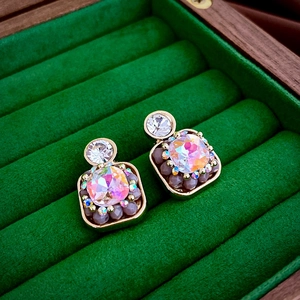 Macro shot of gold square stud earrings with iridescent crystals in a green velvet box