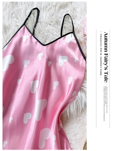 Close-up of pink satin slip dress with white hearts and black trim on fuzzy background