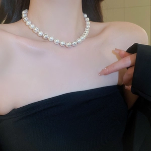 Detail of elegant pearl necklace with silver hollow metal beads on neck