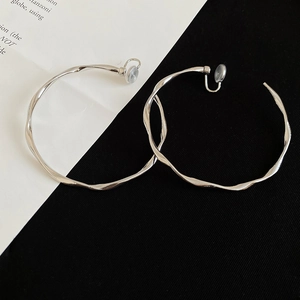Detail of silver twisted hoop earrings with irregular wave texture and clip-on backings