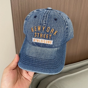 Detailed macro view of retro washed denim baseball cap with orange New York embroidery