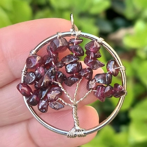 Macro detail of handmade tree of life pendant with silver wire and dark red stones