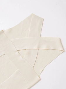 Close-up of cream knit top featuring cross back strap design and fine ribbed texture