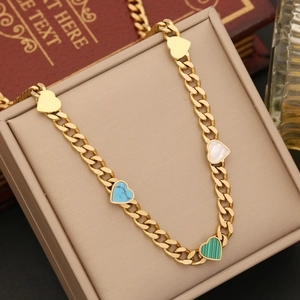 Detail of gold necklace with blue, white, and green heart stone pendants on a beige box
