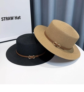 Detail of straw hats with leather bands and gold buckles on a white table
