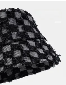 Close-up of checkered bucket hat with distressed raw edges and tweed woven texture