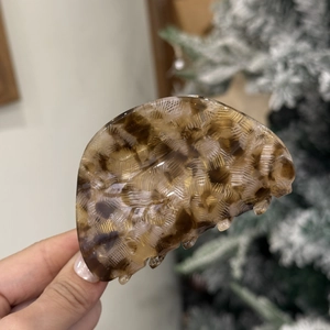 Detailed close-up of a semi-circular acetate hair claw clip with tortoise shell texture and grid