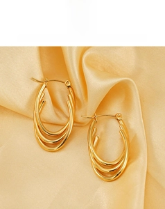 Detailed view of triple-layered golden oval hoop earrings on elegant satin fabric