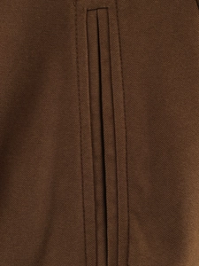 Vue macro du tissu plissé marron et des coutures précises sur la veste courte