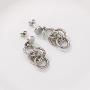 Détail de boucles d'oreilles créoles torsadées argentées au design industriel moderne