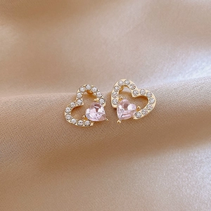 Detail of pink heart crystal stud earrings with gold plating on champagne silk background