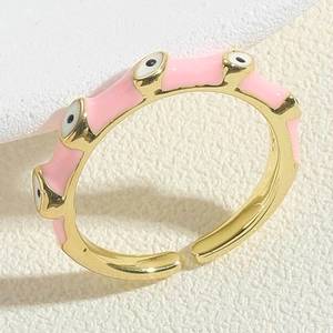Macro shot of gold-plated evil eye ring with pink enamel coating and adjustable band
