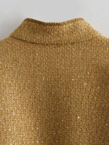 Detailed close-up of ginger tweed fabric with shimmering sequins and stand collar texture