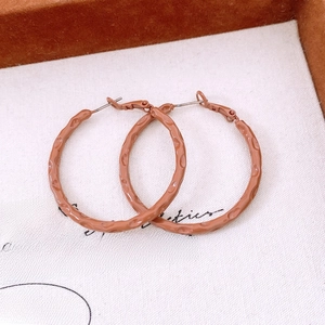 Detail shot of large brown hammered hoops with matte texture and classic circle design