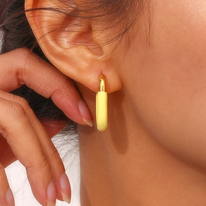 Detailed close-up of U-shaped gold earrings with vibrant yellow enamel finish on ear