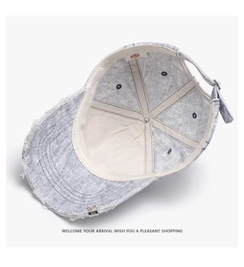 Detail of light blue washed denim baseball cap with distressed brim and metal clip
