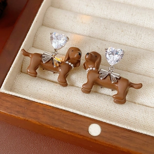 Detail of dachshund earrings with brown finish, silver bow, and crystal heart