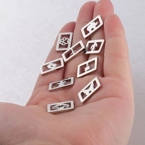 Détails de petits pendentifs en acier inoxydable tenus en main pour voir la taille