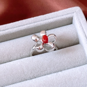 Detail shot of vintage silver flower ring featuring an oval red stone in a jewelry box