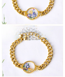 Macro view of gold stainless steel chunky chain bracelet with glass evil eye charm