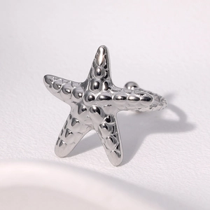 Polished silver starfish ring with minimalist textured design on a white surface