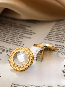 Macro view of vintage gold stud earrings with round crystal on a silk and book backdrop