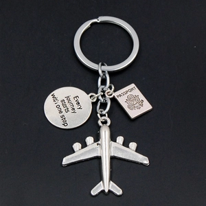 Macro shot of silver airplane keychain with passport charm and inspirational circular tag