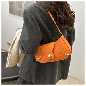 Detail of bright orange faux leather crescent bag with gold twist lock and studs