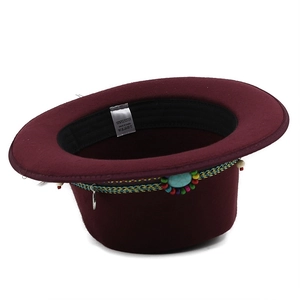 Detail view of burgundy fedora hat with bohemian woven band and turquoise stone decor