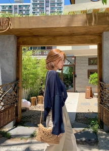 Outdoor street shot of a handwoven paper rope tassel mini bag with a thin shoulder strap