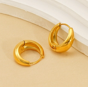 Detailed close-up of thick gold-plated hoop earrings with a polished metallic finish