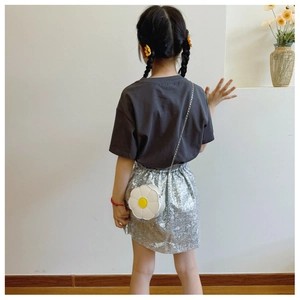 Detail of a white sunflower-shaped kids shoulder bag with a silver chain on a child model