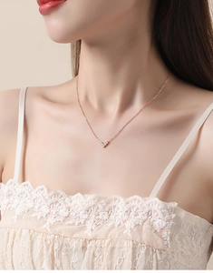 Close-up of a rose gold V-shaped heart pendant necklace with white zircons on a model
