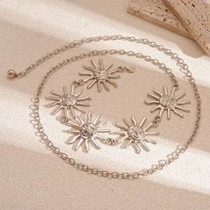 Detail of silver sun god portrait medal and geometric chain links on beige texture