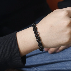 Detail of a black stainless steel double-ring chain bracelet on a male wrist