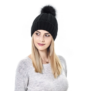 Close-up of black cable knit beanie featuring a large fluffy faux fur pom-pom detail
